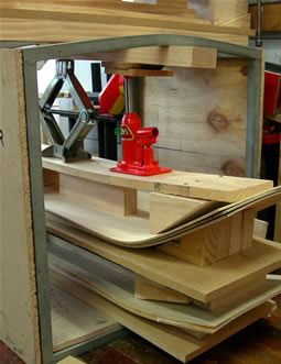 Bending the wood in a press to shape the curvature of the board